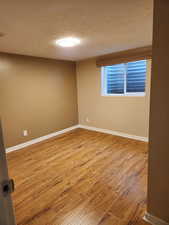 Empty room with wood-type flooring and a textured ceiling