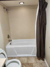 Bathroom featuring toilet and shower / bath combination with curtain