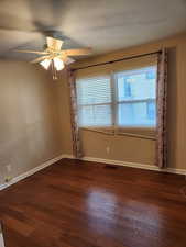 Empty room with dark hardwood / wood-style floors and ceiling fan