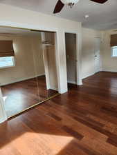 Unfurnished bedroom featuring dark hardwood / wood-style flooring, multiple windows, and ceiling fan