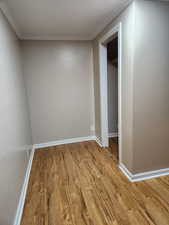 Unfurnished bedroom featuring a closet, light hardwood / wood-style flooring, and crown molding