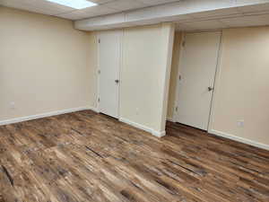 Basement featuring dark wood-type flooring and a paneled ceiling