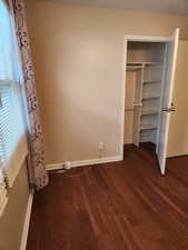 Unfurnished bedroom featuring a closet and dark hardwood / wood-style floors