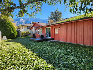 Back of house featuring a lawn and a deck with mountain view