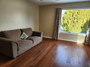 Living room with ceiling fan and dark hardwood / wood-style flooring