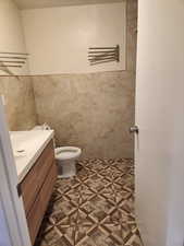 Bathroom featuring tile walls, tile patterned flooring, vanity, and toilet