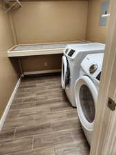 Washroom featuring washing machine and clothes dryer, hardwood / wood-style flooring, and electric panel