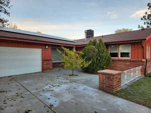 Ranch-style home with a garage and solar panels