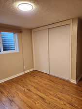 Unfurnished bedroom featuring a closet, light wood-type flooring, and a textured ceiling