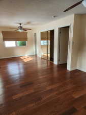 Spare room with a textured ceiling, dark hardwood / wood-style floors, and ceiling fan