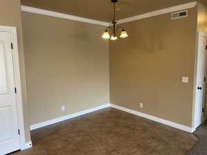 Unfurnished room with a notable chandelier, dark tile patterned floors, and crown molding now that unit is vacant for new owners