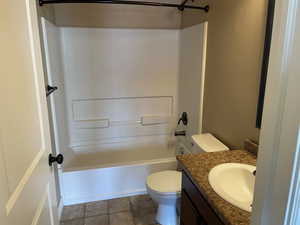 Full bathroom featuring washtub / shower combination, vanity, and toilet now that unit is vacant for new owners