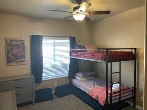 Carpeted bedroom featuring ceiling fan