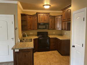 Kitchen with black appliances, crown molding, sink, a textured ceiling, and light tile patterned flooring, now that unit is vacant for new owners