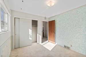 Unfurnished bedroom featuring light colored carpet and a closet