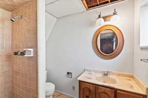 Bathroom with toilet, vanity, and tiled shower