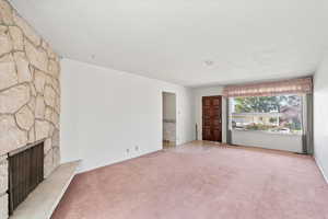 Unfurnished living room featuring a fireplace and light carpet