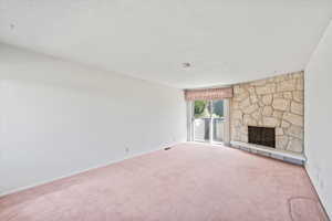 Unfurnished living room with carpet flooring, a fireplace, and a textured ceiling