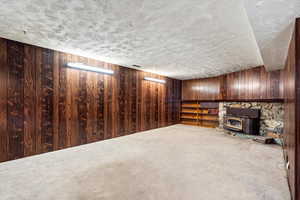 Basement with wooden walls, a textured ceiling, and carpet floors