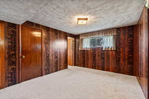 Unfurnished room featuring carpet and wooden walls