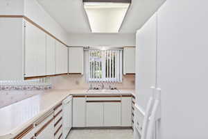 Kitchen featuring dishwasher, sink, and white cabinets