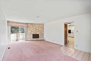 Unfurnished living room with a fireplace, a textured ceiling, and light carpet