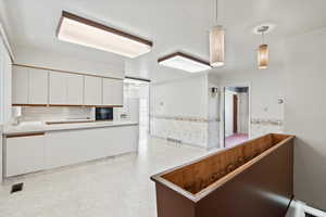 Kitchen featuring white cabinetry, hanging light fixtures, and sink