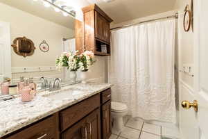 Bathroom with toilet, vanity, and tile patterned floors