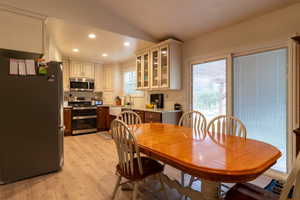 Dining space with light wood-type flooring, lofted ceiling, and sink