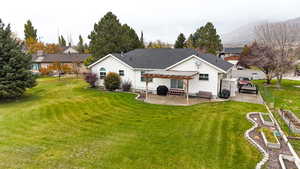 Back of house with mountain view, yard, pergola, and patio area