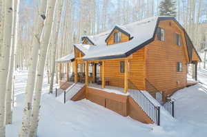 Snow covered back of property featuring covered porch