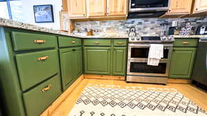 Kitchen featuring stainless steel appliances, light hardwood / wood-style floors, and tasteful backsplash