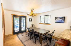 Dining space featuring light hardwood / wood-style floors, a textured ceiling, a notable chandelier, and a healthy amount of sunlight