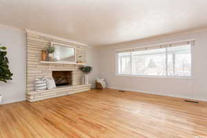 Unfurnished living room with light hardwood / wood-style floors, ornamental molding, and a fireplace