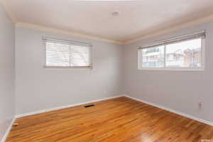 Spare room with ornamental molding and hardwood / wood-style flooring