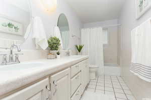 Full bathroom featuring toilet, shower / tub combo, vanity, and tile patterned flooring