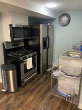 Kitchen with white cabinetry, dark hardwood / wood-style floors, stainless steel appliances, and sink