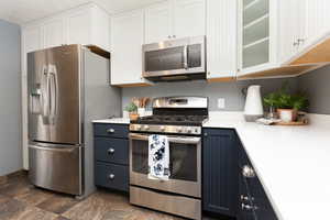 Kitchen with blue cabinetry, white cabinetry, and stainless steel appliances