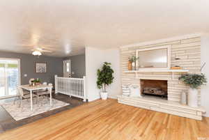 Unfurnished living room with crown molding, a stone fireplace, wood-type flooring, and ceiling fan