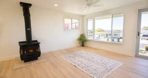 Living room featuring a wood stove, plenty of natural light, light hardwood / wood-style floors, and ceiling fan