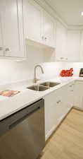 Kitchen featuring dishwasher, light hardwood / wood-style floors, white cabinetry, and sink