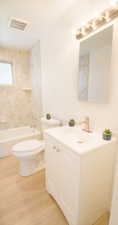 Full bathroom with vanity, hardwood / wood-style flooring, tiled shower / bath, and toilet