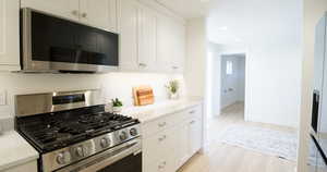 Kitchen with white cabinetry, appliances with stainless steel finishes, and light hardwood / wood-style floors