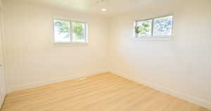 Empty room with light hardwood / wood-style floors, a healthy amount of sunlight, and ceiling fan