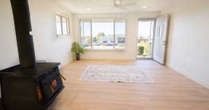 Doorway to outside featuring a wood stove, light hardwood / wood-style flooring, and ceiling fan