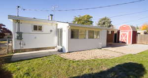 Back of house featuring a lawn, a patio, and a storage unit