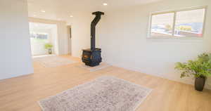 Living room featuring light wood-type flooring, plenty of natural light, and a wood stove