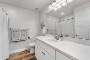 Bathroom featuring wood-type flooring, vanity, and toilet