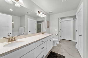 Bathroom featuring walk in shower, vanity, and toilet