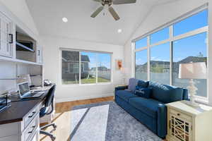 Office area featuring light wood-type flooring, ceiling fan, and vaulted ceiling